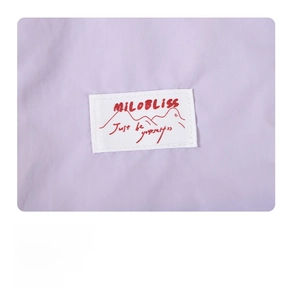Detail of the woven brand label with red logo on the lavender fabric makeup bag