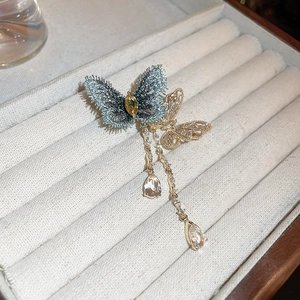 Detailed close-up of a zircon butterfly brooch with elegant tassels and blue wings