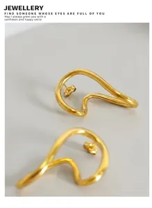 Macro shot of 18K gold plated wavy hoop earrings with high polish on wood decor