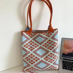 Large knit tote bag with orange and blue geometric diamond patterns on white desk