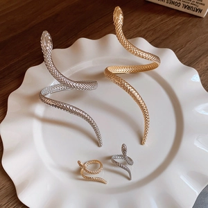 Detailed view of gold and silver snake-shaped arm cuffs and rings with scale textures