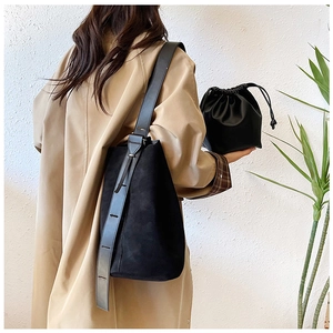 Detail of minimalist black faux suede bucket bag with wide adjustable strap and drawstring pouch