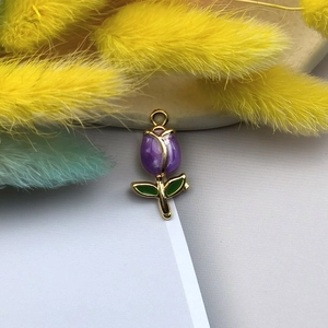 Dettaglio di un ciondolo a tulipano viola con bordo dorato e foglie verdi per gioielli