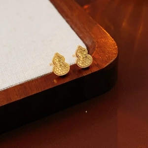 Macro detail of gold-tone gourd studs with unique textured finish on a fabric tray