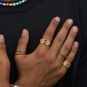 Detailed close-up of layered gold rings including snake and chain patterns on fingers