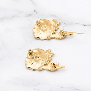 Golden flower brooch back view with pin fastener on white marble background