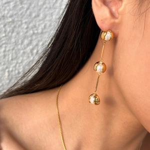 Detail of 18k gold plated long drop earrings with white pearls and tiered tassel design