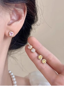 Detailed close-up of square diamond stud earrings in pink, clear, and yellow tones