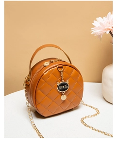 Detailed view of caramel round crossbody bag with quilted texture and cat pendant