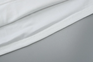 Close-up detail of white textile fabric texture and high-quality stitching on the dress