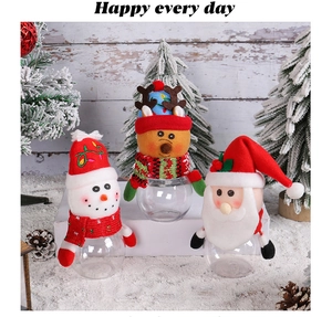 Close-up of Christmas candy jars with snowman and reindeer plush caps on festive wood back