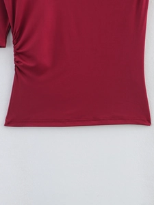 Detail of red asymmetrical T-shirt showing side ruching and flat seam hemline textures