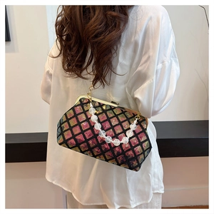 Sparkly sequin shell evening bag with pearl handle chain worn by a model in black