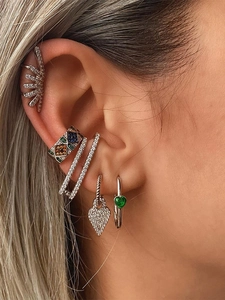 Macro shot of layered bohemian earrings with zircon heart pendant and ear cuffs