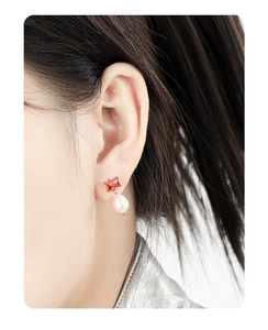 Detail of s925 sterling silver earrings with red zircon and drop-shaped pearl