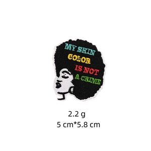 Detail of embroidered patch featuring a Black girl silhouette and social message text