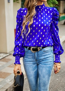 Detail of blue high neck shirt with golden dots, puff sleeves and elastic cuffs in street view