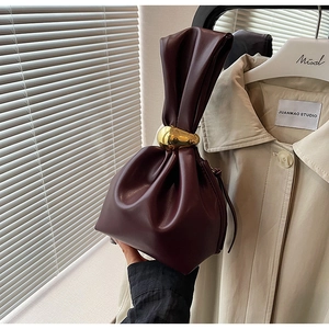 Detailed close-up of dark wine red leather bucket bag with elegant gold ring handle