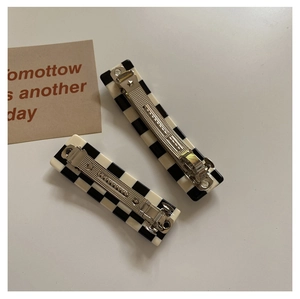 Detailed view of large black and white checkered hair claw clips with metal spring mechanism