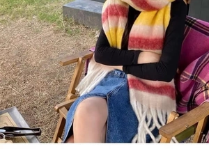 Close-up of a gradient plaid scarf with fringes worn by a woman sitting outdoors
