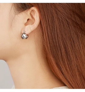 Detail of silver S925 spherical earring showing CNC laser cut texture on earlobe