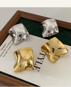 Close-up of gold and silver irregular square earrings displayed on a white card