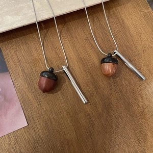 Detailed macro view of creative wooden acorn pendants on sleek silver snake chains
