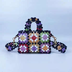Close-up of handmade beaded bag featuring colorful floral patterns and gold metal buckles