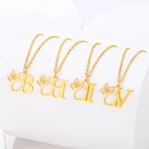 Detailed view of four golden letter pendants with profile silhouettes on a white stand