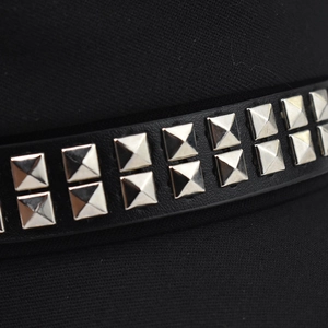 Detailed macro view of black beret featuring double rows of square silver metal rivets