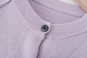 Detail of lavender knit cardigan showing ribbed neckline and black button close-up