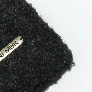 Detail of black boucle knit hat featuring a luxury gold metallic MBK brand plate