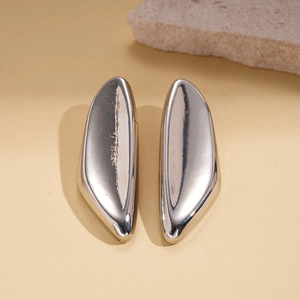 Detailed view of silver irregular geometric oval stud earrings on stone texture backdrop