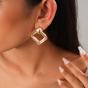 Gros plan d'un mannequin portant des boucles d'oreilles géométriques dorées élégantes