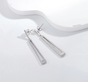 Macro shot of silver geometric earrings with micro-paved zircons and fringe details
