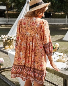 Vue de dos d'une robe bohème orange à fleurs avec manches trois-quarts dans un jardin