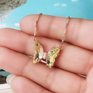 Detailed close-up of rose gold butterfly pendant necklace with yellow crystal wings