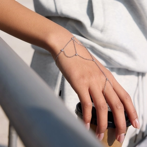 Silver finger bracelet with zircon charms on model hand holding coffee cup