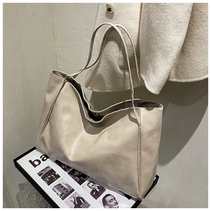 Detail of soft cream faux leather tote bag with magnetic closure on art book tray