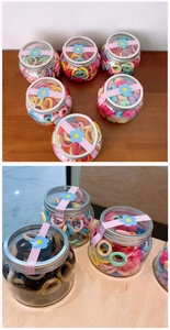 Close-up of assorted colorful elastic hair ties packaged in transparent jars for girls