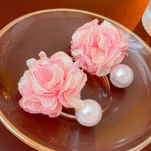Macro detail of pink organza flower earrings with large imitation pearls on a tray