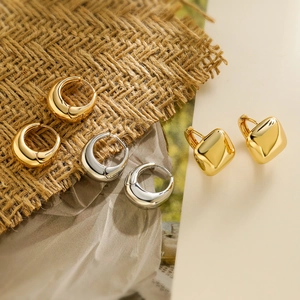 Close-up of minimalist gold and silver geometric hoop earrings on linen backdrop