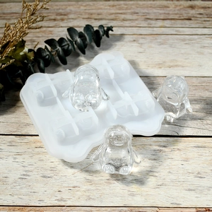 Detailed view of 4-cavity penguin silicone ice mold with clear penguin-shaped ice cubes