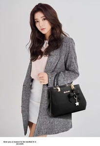 Detailed view of black litchi leather handbag featuring a bow and gold floral pendant