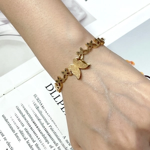 Close-up of golden butterfly bracelet with frosted texture on woman's wrist