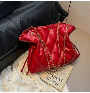 Close-up of red quilted PU leather bucket bag with gold chain strap and drawstring
