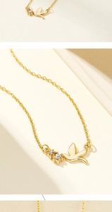 Detailed close-up of 18K gold-plated bird pendant with sparkling crystal accents