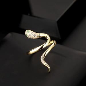Macro shot of gold snake ring featuring white zircon pavé and green gem eyes