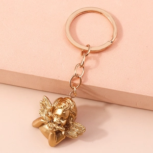 Detail of a golden angel keychain with satin finish and intricate musical instrument design