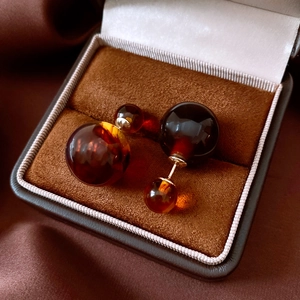 Detail view of amber resin double ball earrings on a brown velvet jewelry box